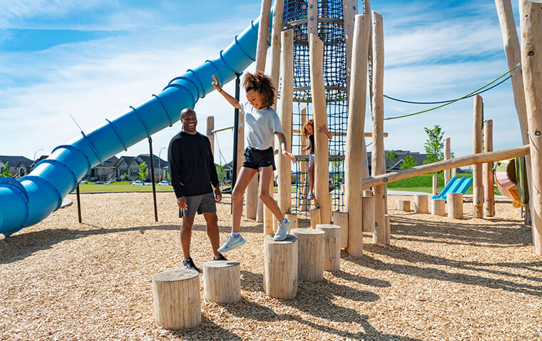 A father watches his daughter playing on the playground apparatus